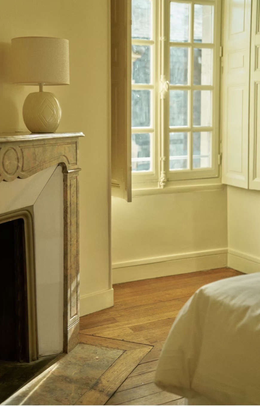 A bedroom with fireplace and window light