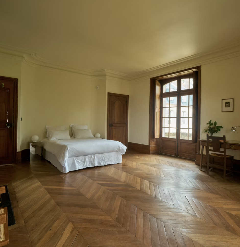 A spacious château bedroom with tall windows